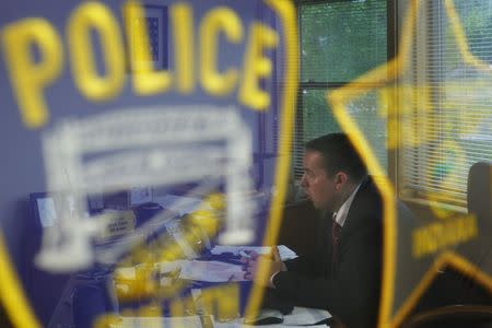 Lewiston Police Chief Michael Bussiere is reflected in a display of police badges while being interviewed by Reuters in Lewiston, Maine June 1, 2015. REUTERS/Brian Snyder