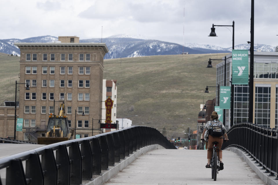 A cyclist rides over the Beartracks Bridge in Missoula, Mont., Tuesday, April 25, 2023. It was little surprise that Missoula, a college town where pride flags are a common sight, sent Zooey Zephyr to the state legislature. Zephyr, the first openly transgender legislator in Montana’s history, was barred last week from speaking on the floor of the legislature by the Republican majority. (AP Photo/Tommy Martino)