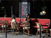 Women sit on the terrace of a cafe in Paris, Tuesday, June 2, 2020. Parisians who have been cooped up for months with take-out food and coffee will be able from Tuesday to savor their steaks tartare in the fresh air and cobbled streets of the City of Light once more -- albeit in smaller numbers. (AP Photo/Thibault Camus)
