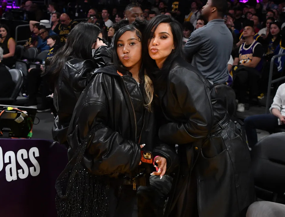 Kim Kardashian and her daughter North West posing together courtside, making kissy faces, at a basketball game