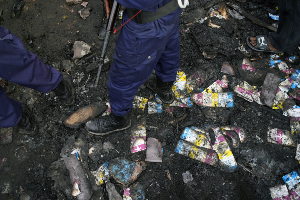 Police stand on burned ballot in the mud at the entrance of the Les Anges primary school in Kinshasa, Congo,Sunday Dec. 30, 2018. The voting process was delayed when angry voters burned six voting machines and ballots mid-day, angered by the fact that the registrations lists had not arrived. Replacement machines had to be brought in, and voting started at nightfall, 12 hours late. Forty million voters are registered for a presidential race plagued by years of delay and persistent rumors of lack of preparation. (AP Photo/Jerome Delay)