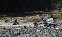 Damaged cars lay in riverbed after flooding in Drolenval, Belgium, Saturday, July 17, 2021. Uncontrollable water destroyed several towns, leaving tons of debris in its wake in one of the most violent natural disasters to hit Belgium in a century. (AP Photo/Virginia Mayo)