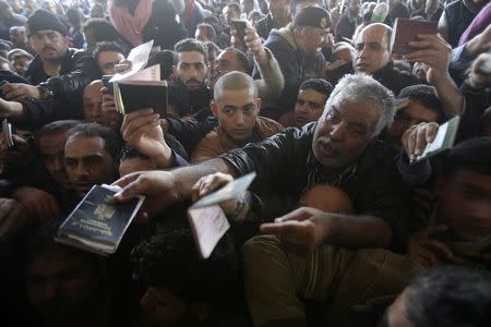 Palestinians, hoping to cross into Egypt, present their passports at the Rafah crossing between Egypt and the southern Gaza Strip December 21, 2014. REUTERS/Ibraheem Abu Mustafa