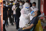A doctor collects a sample for a coronavirus test outside a clinic in Kajang on the outskirts of Kuala Lumpur, Malaysia, Friday, Oct. 23, 2020. Malaysia restricted movements in its biggest city Kuala Lumpur, neighbouring Selangor state and the administrative capital of Putrajaya from Wednesday in an attempt to curb a sharp rise in coronavirus cases. (AP Photo/Vincent Thian)