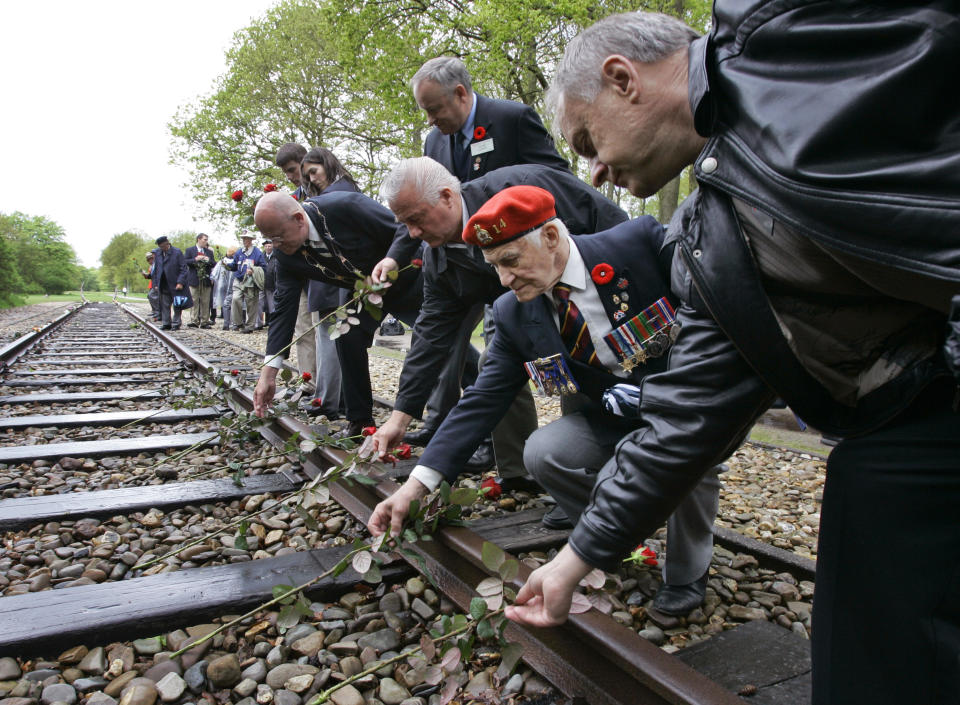 In this Monday May 9, 2015, file photo, Canadian World War II veterans put roses on the railroad tracks at former concentration camp Westerbork, the Netherlands, Monday May 9, 2005. The veterans observed a minute of silence remembering more than a hundred thousand Jews who were transported from Westerbork to Nazi death camps. The Dutch national railway company NS says it will set up a commission to investigate how it can pay individual reparations for its role in mass deportations of Jews by Nazi occupiers during World War II. (AP Photo/Peter Dejong)