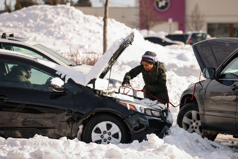 Una mujer ayuda a arrancar un automóvil abandonado después de que fue remolcado a un estacionamiento luego de una tormenta de invierno en Buffalo, Nueva York, EEUU