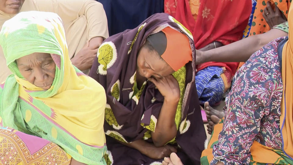 In this video grab provided by Television of Mozambique, women mourn their relatives in Nampula, Mozambique, Monday April 8, 2024, after a makeshift ferry overcrowded with residents reportedly fleeing a cholera outbreak sank off Mozambique's northern coast on Sunday, killing at least 98 people including children. (Television Mozambique via AP)