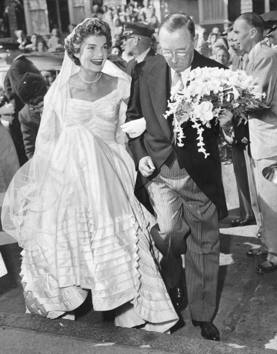 A smiling Jacqueline Bouvier arrives at St. Mary's Church in Newport, R.I., on the arm of her stepfather, Hugh D. Auchincloss, for her wedding. (Photo by Pat Candido/NY Daily News Archive via Getty Images)