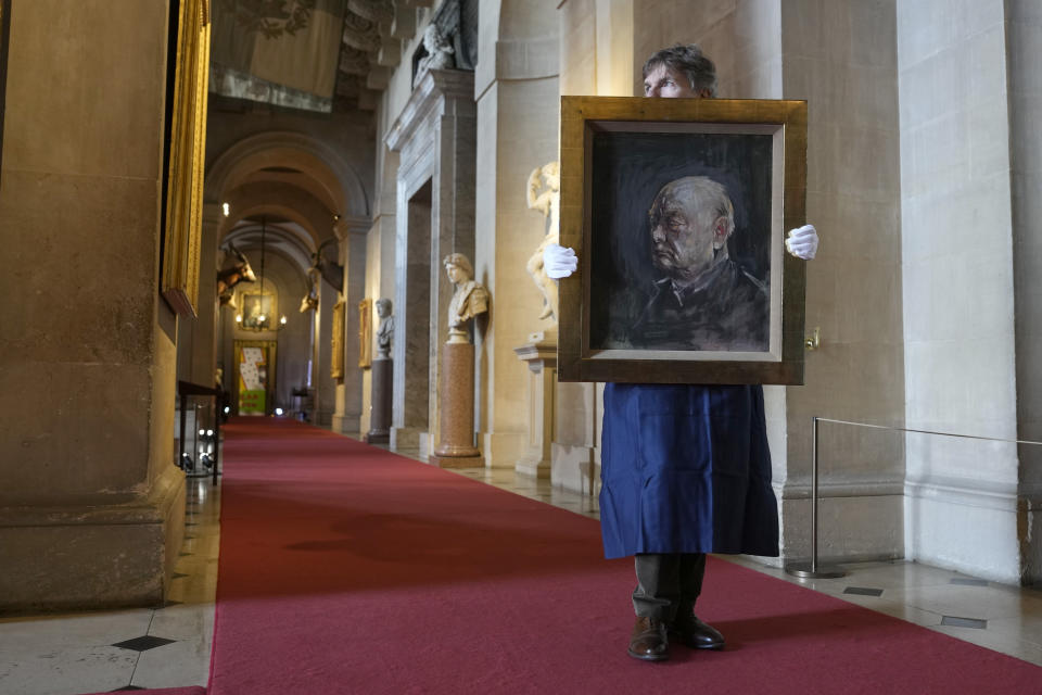 A member of staff from Sotheby's poses for the media with a portrait of the iconic former British Prime Minister Winston Churchill, painted by Graham Sutherland in 1954, at Blenheim Palace, Woodstock, England, Tuesday, April 16, 2024. The portrait will be sold at auction on June 6 with an estimated price of 500-800,000 pounds sterling (US621, 000-1,000,000). Churchill was born at Blenheim Palace on Nov. 30, 1874. (AP Photo/Alastair Grant)