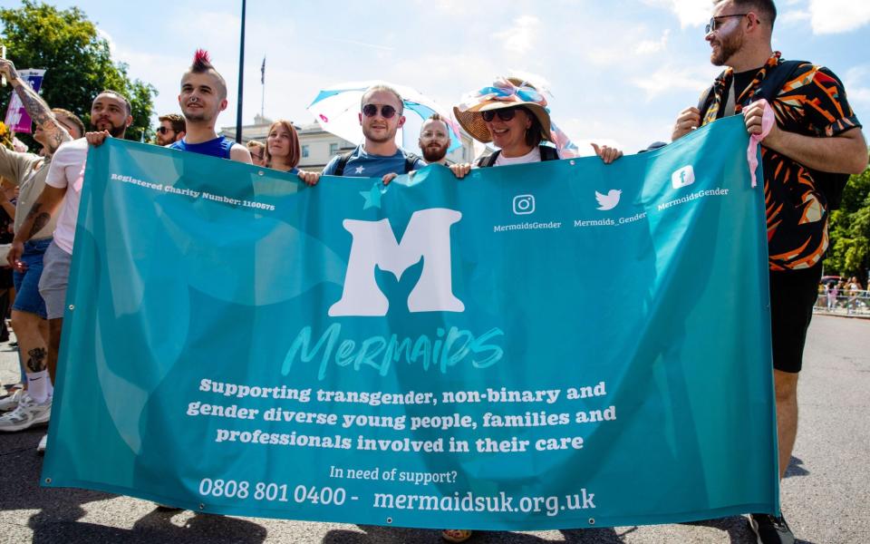 Campaigners march behind a Mermaids UK banner at the London Trans+ Pride march - Alamy
