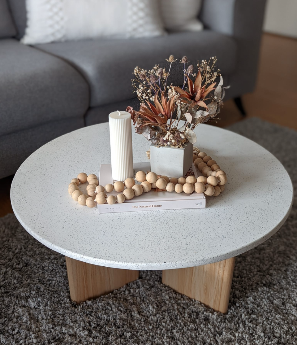 Hacked Kmart and Bunnings coffee table, styled with flowers, candle, beads and book on top