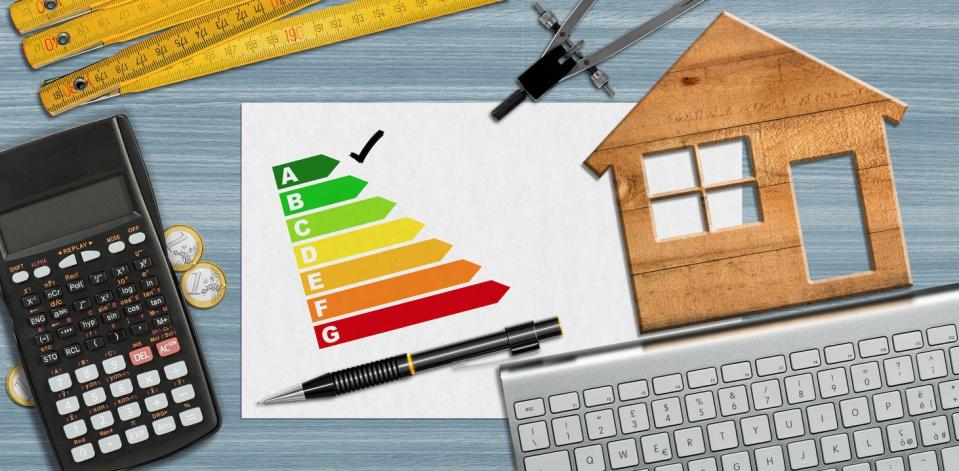 desktop with keyboard and calculator and small house symbol with energy rating system home efficiency concept