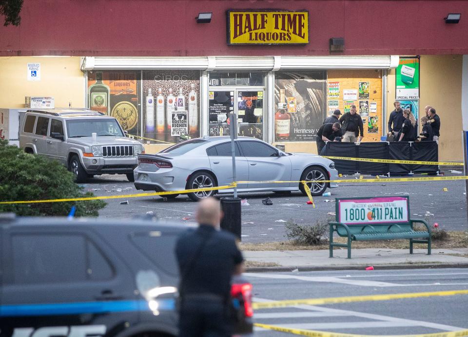 Police work in front of Half Time Liquors on Pensacola Street following a shooting Saturday night that killed at least one person and injured eight.