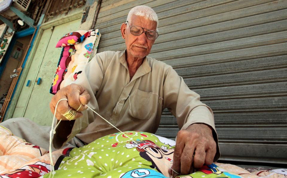Abu Abdul Razzaq, 74, sews blankets on the streets of Baghdad, Iraq. Razzaq is one of the last people to work in a local industry that is being replaced by imports from China and other countries.