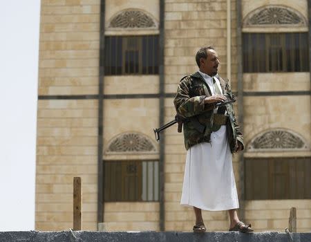 A Houthi militant stands guard on a wall outside the headquarters of the United Nations in Sanaa April 15, 2015. REUTERS/Khaled Abdullah