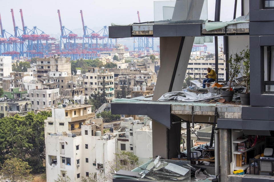 A man sits between debris inside his house damaged by Tuesday's explosion in the seaport of Beirut, Lebanon, Friday, Aug. 7, 2020. The U.N. human rights office is calling for an independent investigation into the deadly explosion, insisting "victims' calls for accountability must be heard." (AP Photo/Hassan Ammar)