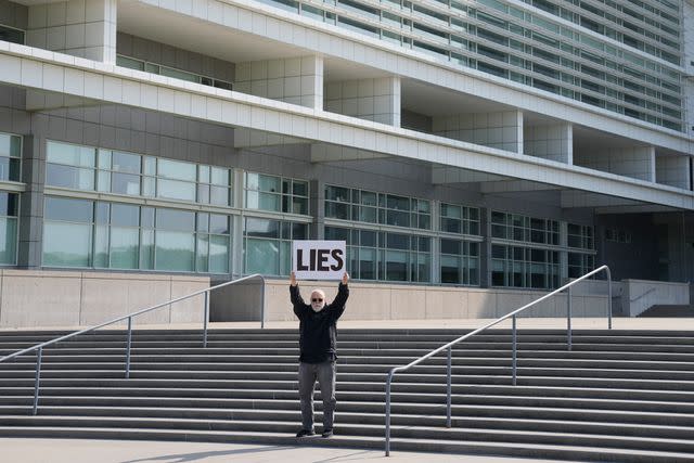AP Photo/Seth Wenig A protestor stands outside of the federal courthouse in Central Islip, New York, where George Santos was arraigned