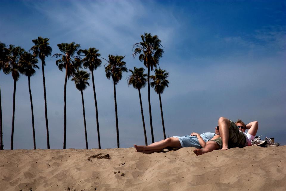 A couple takes in the sun at the beach near Stearns Wharf in Santa Barbara on Mar. 28, 2013.