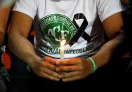 A fan of Atletico Nacional soccer club holds a candle and wears a shirt in support while paying tribute to the players of Brazilian club Chapecoense killed in the recent airplane crash, in Medellin, Colombia, November 30, 2016. REUTERS/Jaime Saldarriaga