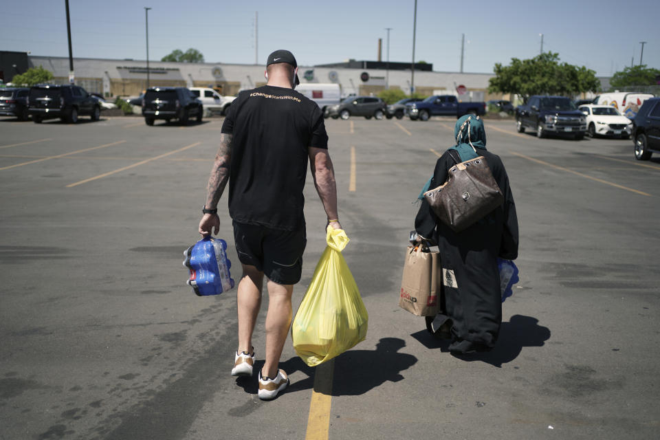 In this photo taken Friday, June 5, 2020, Minnesota Vikings NFL football player Kyle Rudolph helps a woman carry items to her car at the "Change Starts with Me" food and household supply giveaway outside a Cub Foods store in Minneapolis. George Floyd was killed less than three miles from the stadium where the Minnesota Vikings play, so this global unrest over racial relations and justice hit awfully close to home for the team. (Brian Peterson/Star Tribune via AP)