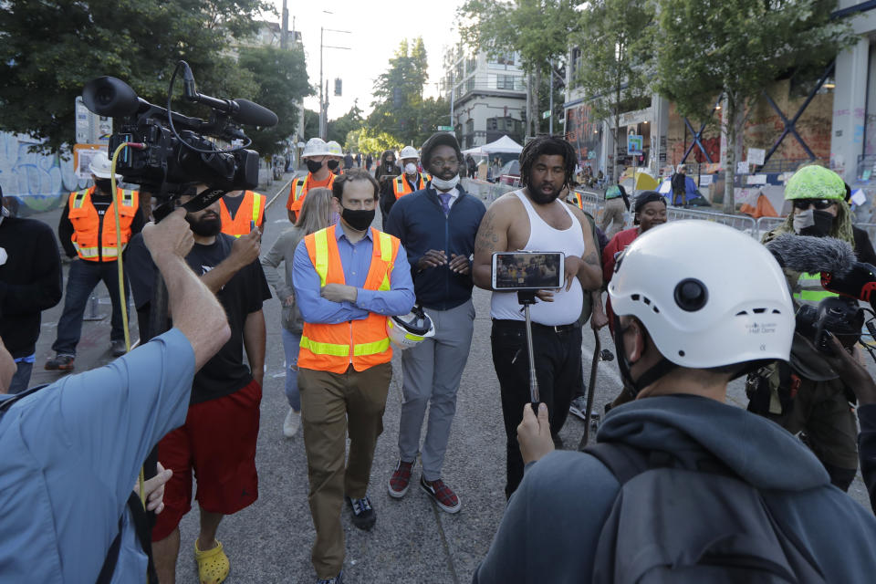 Seattle Department of Transportation workers walk and talk with protest organizers near the Seattle Police Department East Precinct building after SDOT arrived at the the CHOP (Capitol Hill Occupied Protest) zone in Seattle, Friday, June 26, 2020, with the intention of removing barricades that had been set up in the area. Several blocks in the area have been occupied by protesters since Seattle Police pulled back from their East Precinct building following violent clashes with demonstrators earlier in the month. (AP Photo/Ted S. Warren)