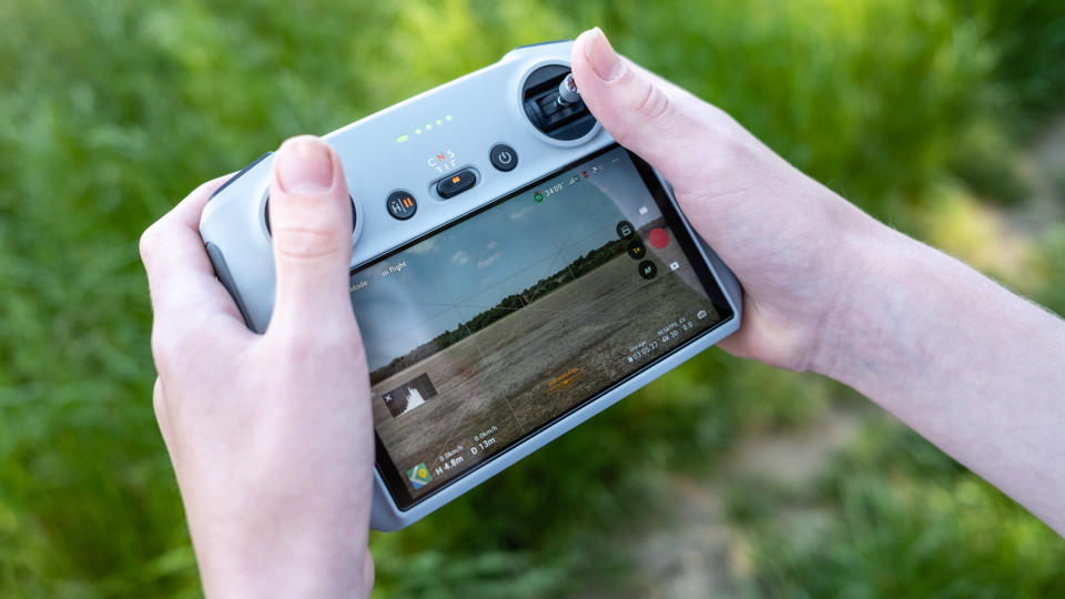 A drone remote controller in the hand with drone in flight