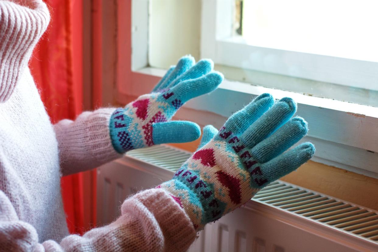 Hands in wool gloves on radiator