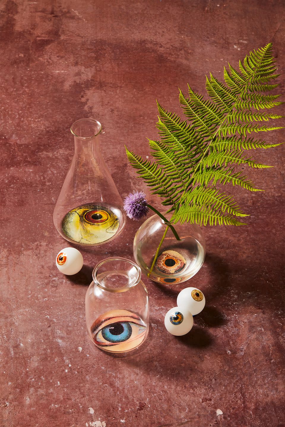 <p>Use these eerie vessels as vases, or as cocktail glasses (they're food safe as long as the liquid doesn't come in contact with the decoupaged artwork). Gather a mix of clean recycled bottles and jars, <a href="https://www.jamaligarden.com/4in-smoke-ball-bud-vase.html" rel="nofollow noopener" target="_blank" data-ylk="slk:bud vases;elm:context_link;itc:0;sec:content-canvas" class="link ">bud vases</a> and chemistry <a href="https://www.jamaligarden.com/6in-lab-glass-bud-vase-set-of-4.html" rel="nofollow noopener" target="_blank" data-ylk="slk:flasks;elm:context_link;itc:0;sec:content-canvas" class="link ">flasks</a>, then <a href="https://hmg-prod.s3.amazonaws.com/files/gh-halloween-artwork-1597083176.pdf?tag=syn-yahoo-20&ascsubtag=%5Bartid%7C10055.g.33437890%5Bsrc%7Cyahoo-us" rel="nofollow noopener" target="_blank" data-ylk="slk:download our eyeball clip art;elm:context_link;itc:0;sec:content-canvas" class="link ">download our eyeball clip art</a> and print onto regular printer paper. Cut out the eye shapes to fit to the bottom of the jars. Paint a thin layer of Mod Podge to the bottom exterior of the glass and place your cut paper (artwork-side down) on top. Smooth out any air bubbles or wrinkles with your fingers and let dry. Paint on a couple additional layers of Mod Podge to seal and let dry several hours. <br></p>