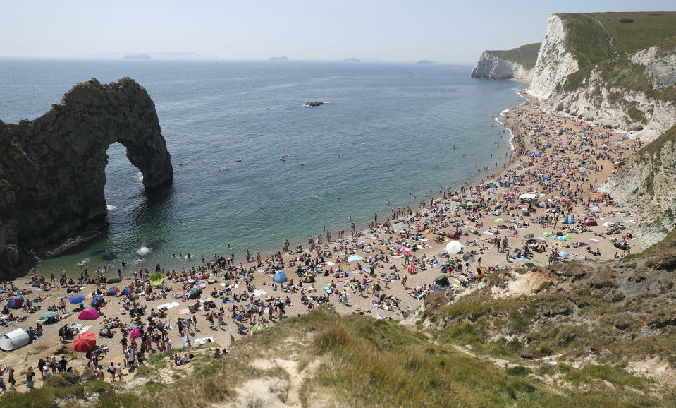 People on the beach at Durdle Door, as the public are being reminded to practice social distancing following the relaxation of coronavirus lockdown restrictions, near Lulworth in Dorset, England, Saturday, May 30, 2020. (Andrew Matthews/PA via AP)