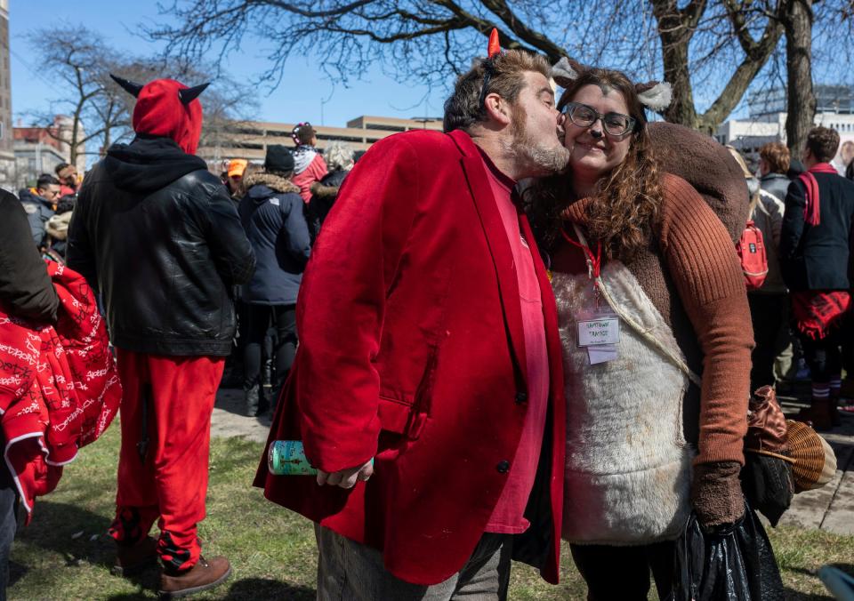 David Grogan, left, kisses his friend, Lynn Blasey, program manager of the Community Arts Partnerships office at the College for Creative Studies, on the cheek during the Marche du Nain Rouge 2024 parade in Detroit on Sunday, March 24, 2024.