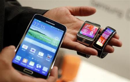 The new Samsung Galaxy S5 smartphone (L), Gear 2 smartwatch (C) and Gear Fit fitness band are displayed at the Mobile World Congress in Barcelona February 23, 2014. REUTERS/Albert Gea