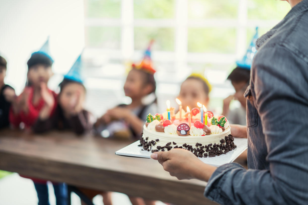 Group of Asian adorable kids looking at birthday cake with candle.