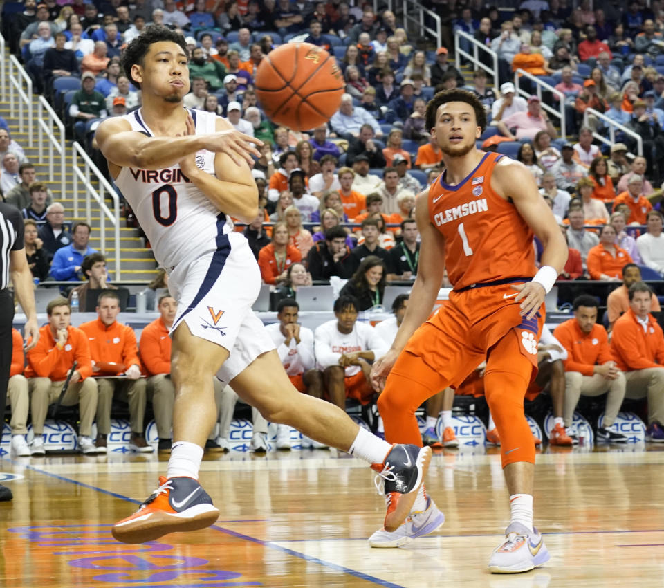 Virginia guard Kihei Clark (0) passes the ball as he goes out of bounds as Clemson guard Chase Hunter (1) watches during the first half of an NCAA college basketball game at the Atlantic Coast Conference Tournament in Greensboro, N.C., Friday, March 10, 2023. (AP Photo/Chuck Burton)