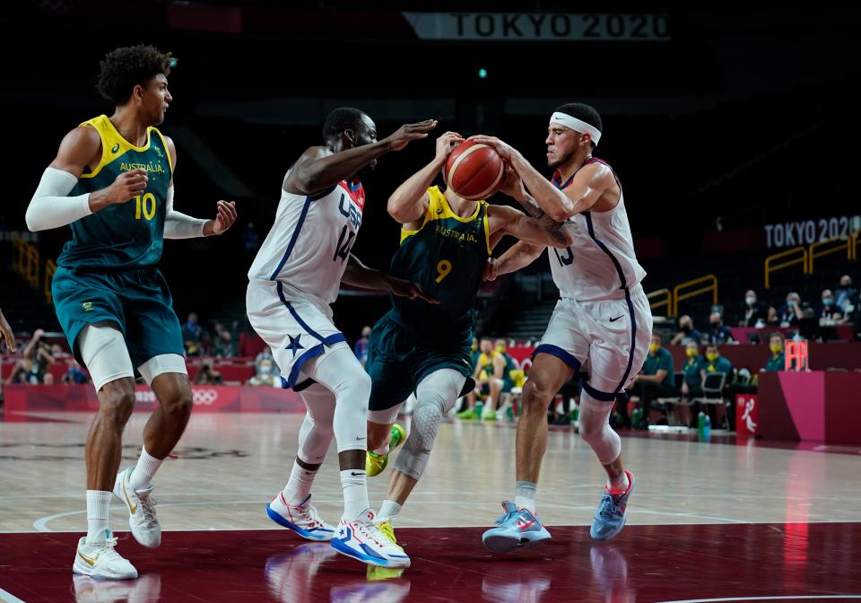 Australia's Nathan Sobey (9) second right, drives between United States's Devin Booker (15), right, and United States's Draymond Green (14) during men's basketball semifinal game at the 2020 Summer Olympics, Thursday, Aug. 5, 2021, in Saitama, Japan. (AP Photo/Charlie Neibergall).