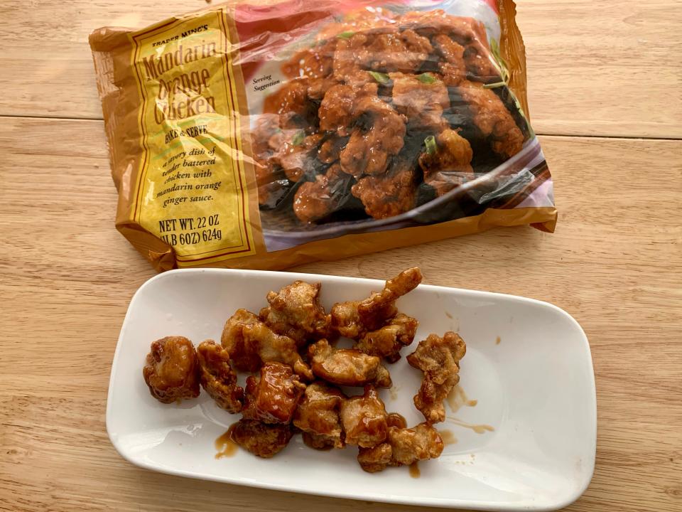 trader joe's orange chicken on white plate with orange bag beside it