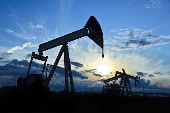 A group of oil pumps with the sun behind them.