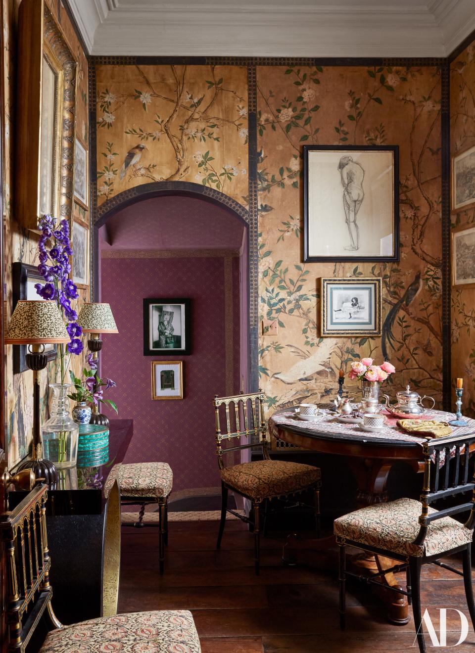 A restored 18th-century chinoiserie wallpaper covers the dining room. Drawings by Louise Bourgeois and Tomaso Buzzi. In hallway beyond, photo by Inge Morath and sketch by Hervé Van der Straeten.