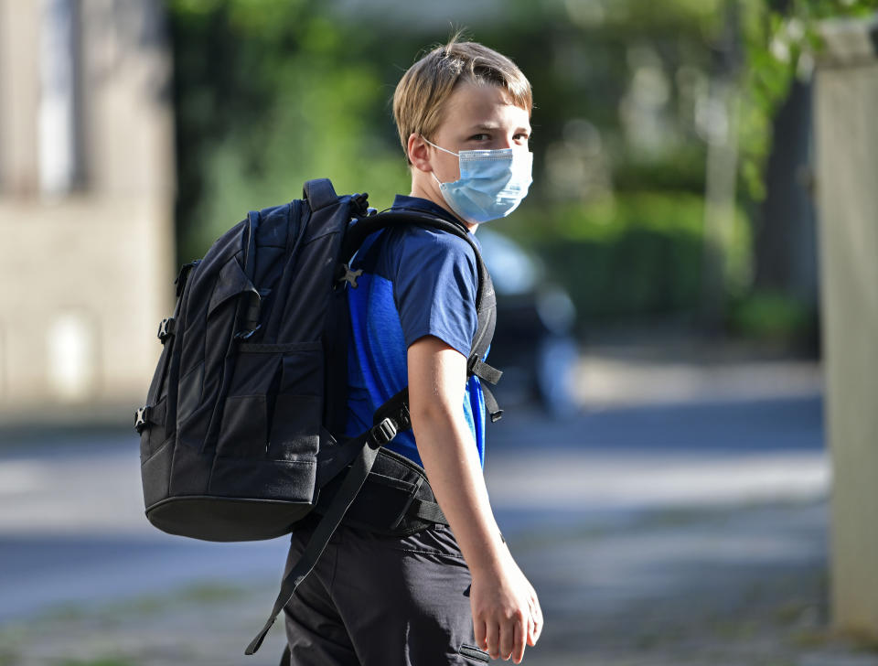 Pupil Moritz is on his way to the first day at his new school in Gelsenkirchen, Germany, Wednesday, Aug. 12, 2020. Students in North Rhine-Westphalia will have to wear face masks at all times due to the coronavirus pandemic as they return to school this Wednesday. (AP Photo/Martin Meissner)