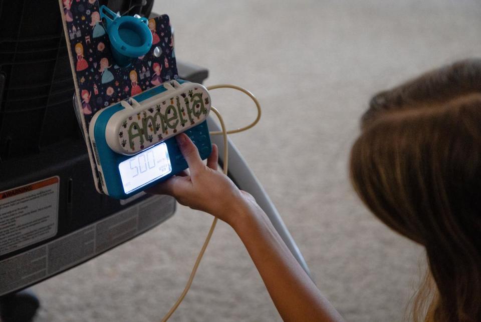 Avery Whites, 13, checks on her sister Amelia, 3, during lunch by looking at the machine and gastrostomy tube that she uses to eat, at their home in New Braunfels, on July 27, 2023.