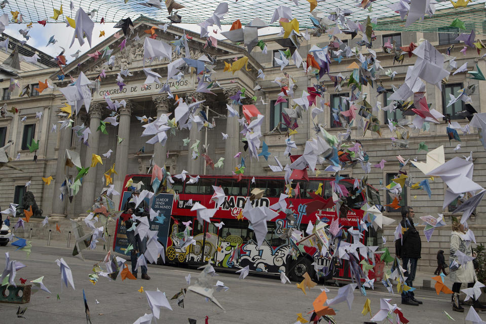 Paper birds hang on strings outside the Spanish Parliament