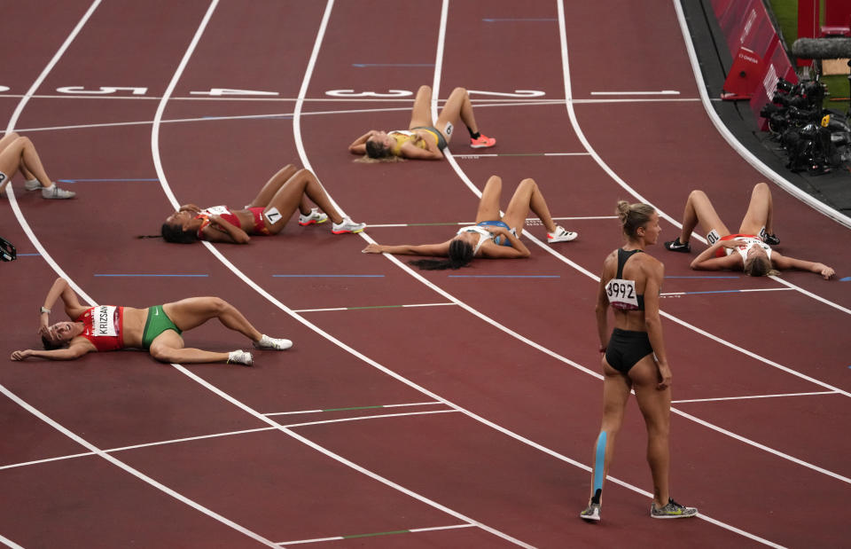 Heptathletes lay on the track after finishing the heptathlon 1500-meters at the 2020 Summer Olympics, Thursday, Aug. 5, 2021, in Tokyo, Japan. (AP Photo/Charlie Riedel)