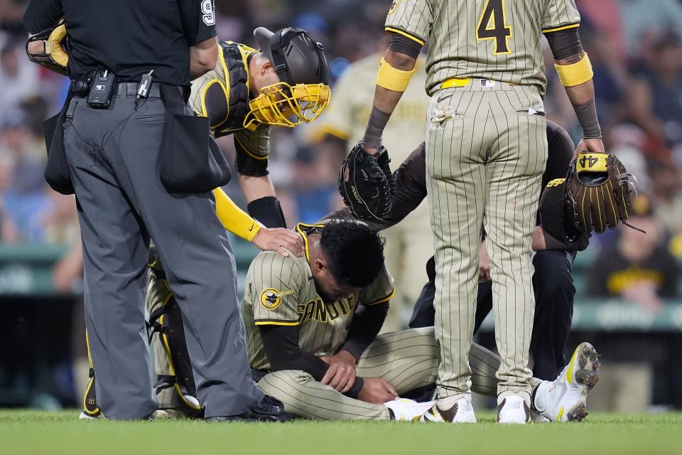 San Diego Padres starting pitcher Randy Vásquez, center, holds his arm between teammates catcher Kyle Higashioka, second from left, and first baseman Luis Arraez (4) after deflecting the line-drive single by Boston Red Sox's Ceddanne Rafaela during the fifth inning of a baseball game, Friday, June 28. 2024, in Boston. (AP Photo/Michael Dwyer)