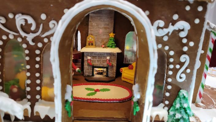 An illuminated fireplace, furniture made of icing and a gingerbread radio can be seen inside a window on the Best in Show winner: a three-story &quot;Santa&#39;s Gingerbread Dollhouse&quot; by Kenda DeFord.