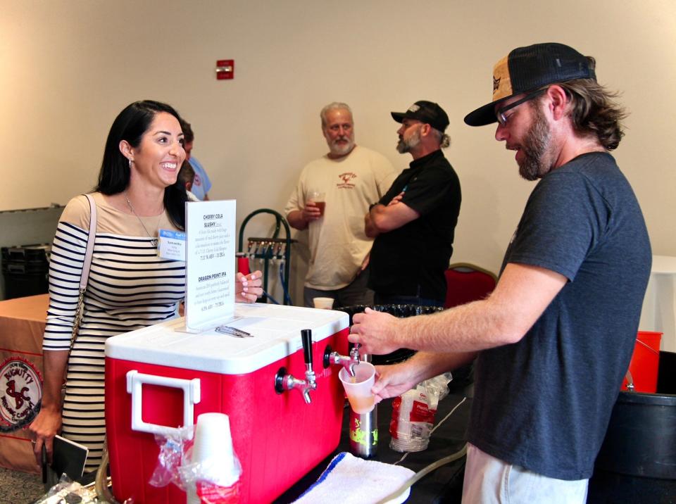 Chris Ayers of Intracoastal Brewing Co., right, pours a beer for Samantha Selig at the Economic Development Commission of Florida's Space Coast board meeting and investor update in August in Cocoa Village.