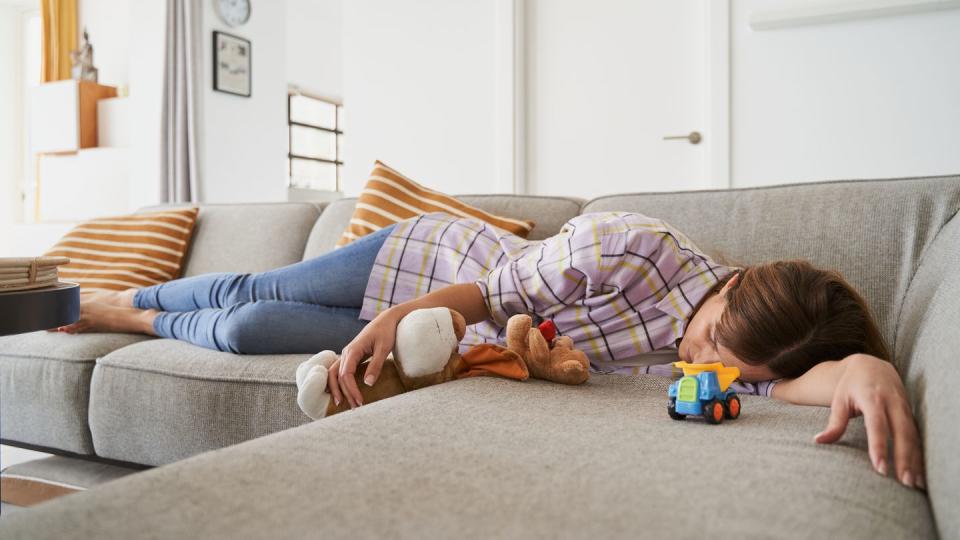 mother lying on the sofa at home tired after playing and taking care of her children