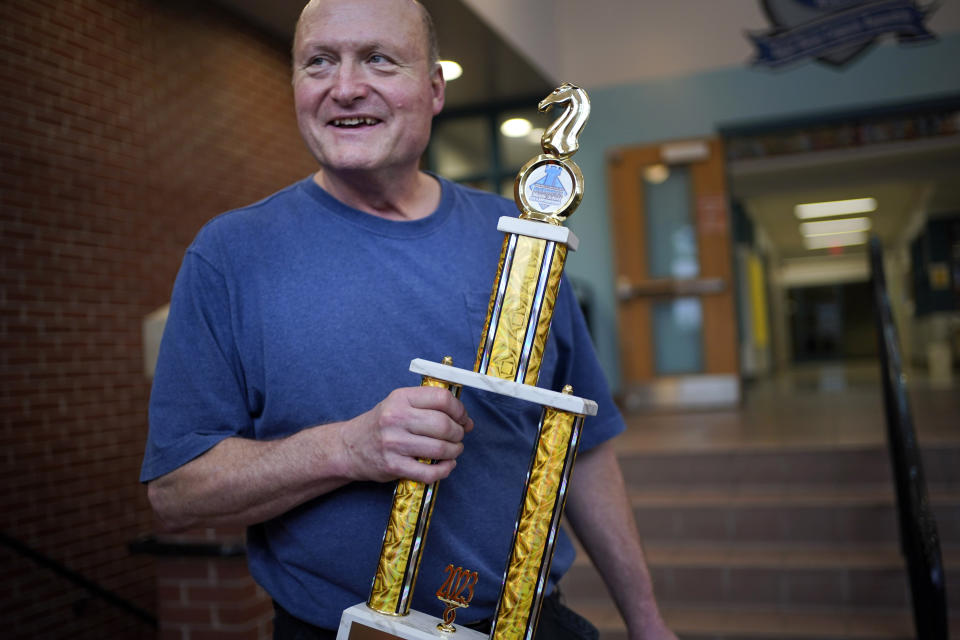 Custodian David Bishop holds the trophy recently won by the Reeds Brook Middle School chess team in a national competition, Tuesday, April 25, 2023, in Hampden, Maine. Bishop coached his schools' chess team to an 8th place finish out of 52 schools in the 2023 National Middle School Championships in Round Rock, Texas. (AP Photo/Robert F. Bukaty)