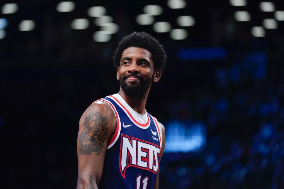 Kyrie Irving looks to his right and smiles during a Nets game in 2022.