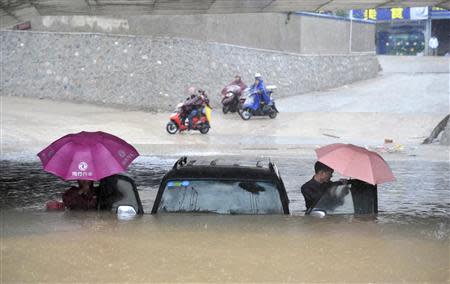 People get out of a stranded car at a flooded underpass amid heavy rainfalls under the influence of Typhoon Haiyan, in Nanning, Guangxi Zhuang autonomous region November 11, 2013. REUTERS/China Daily