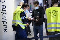 Security staff of the EPFL Covid Angels control the Covid Certificate of students before they enter into an auditorium at the Swiss Federal Institute of Technology, EPFL, in Lausanne, Switzerland, Tuesday, Sept. 21, 2021. The Covid pass will be required from 20 September for students to attend classes in person. (Laurent Gillieron/Keystone via AP)