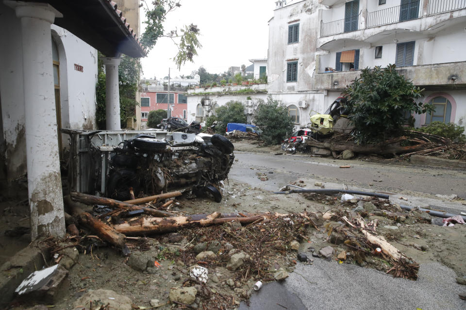 Damaged vehicles lie by a road after heavy rainfall triggered landslides that collapsed buildings and left as many as 12 people missing, in Casamicciola, on the southern Italian island of Ischia, Saturday, Nov. 26, 2022. Firefighters are working on rescue efforts as reinforcements are being sent from nearby Naples, but are encountering difficulties in reaching the island either by motorboat or helicopter due to the weather. (AP Photo/Salvatore Laporta)